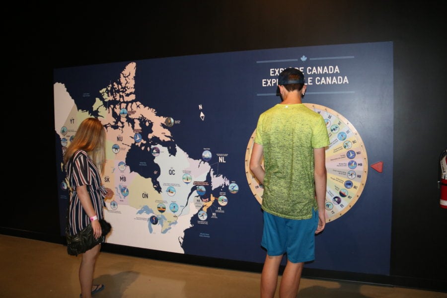 Lucas and Jessica spinning a wheel and matching the result to a map to explore locations in Canada at the Canada Science and Technology Museum