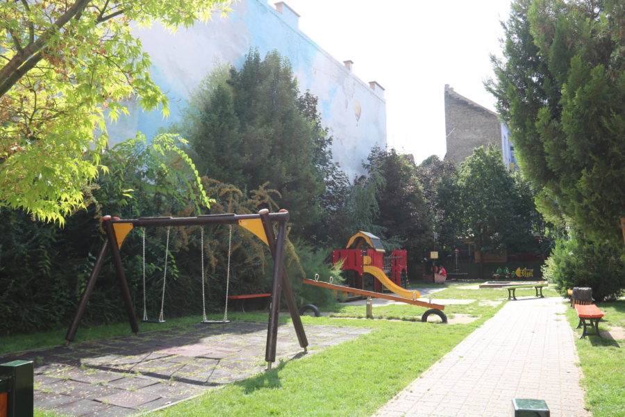 image taken of playground with swings and slide and grass with painted wall