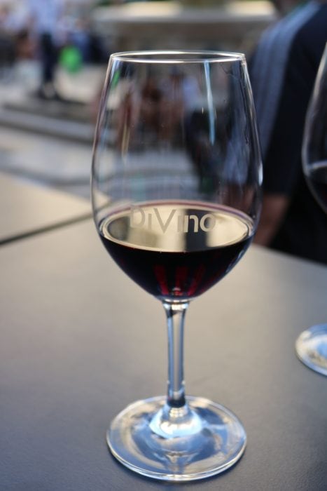 image of wine glass half full of red wine with Devino etched in the glass