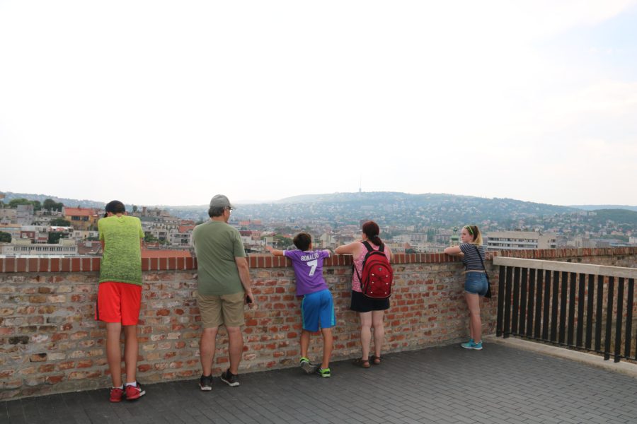 image of five people leaning on a stone wall looking at the buda hills in distance