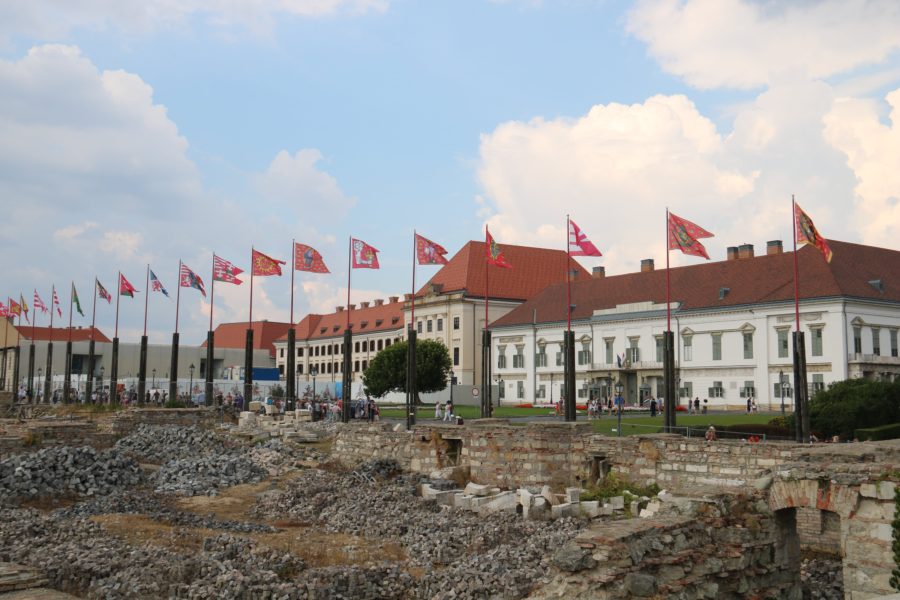 image of a white and yellow building behind a series of flags at Budapest's castle hill
