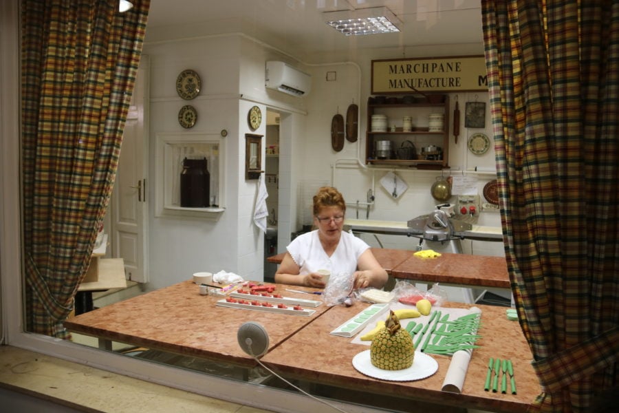 image of lady sitting behind glass window making cars with marzipan on our Danube Bend tour