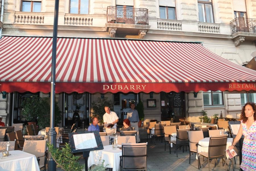 exterior of Dubarry restaurant Budapest with red and white striped awning over patio tables one of best Hungarian restaurants in Budapest