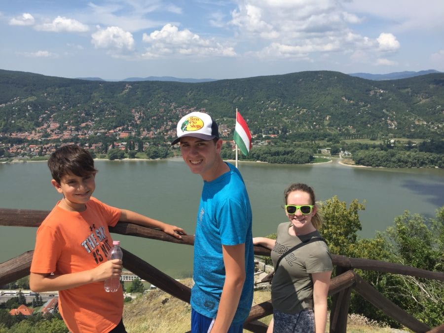 Image of three kids looking over Danube River with Hungary flag flying on day trip from Budapest