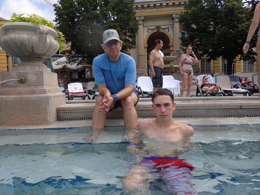 John sitting outside the pool and Lucas sitting in the pool beside John enjoying the Szechenyi Baths