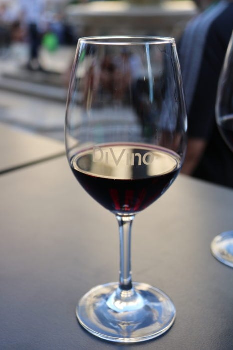 a wine glass with Devino etched half full of red wine