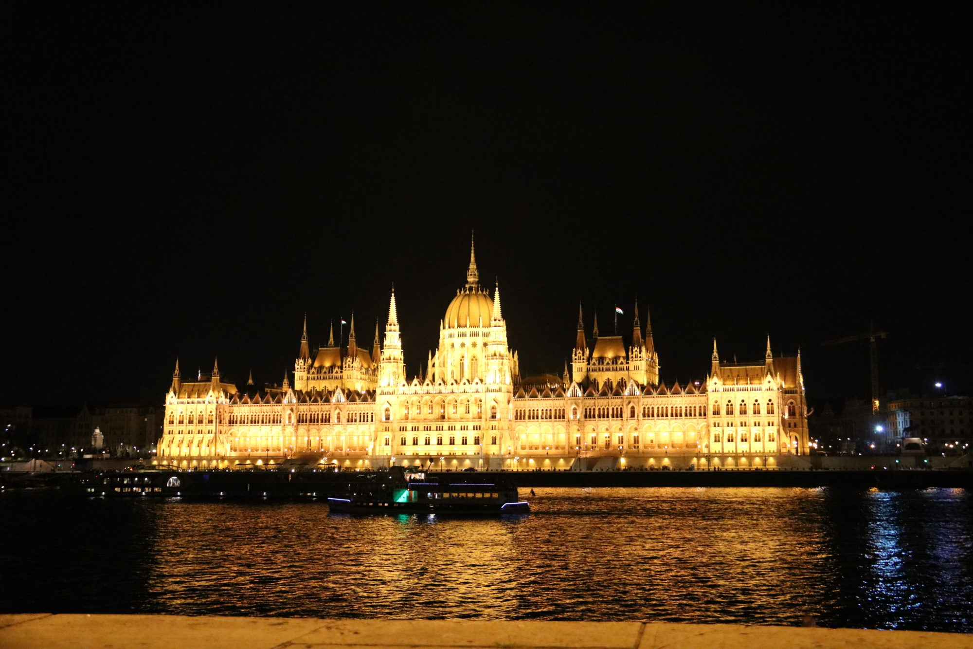 Hungarian Parliament glows at night reflecting in the Danube