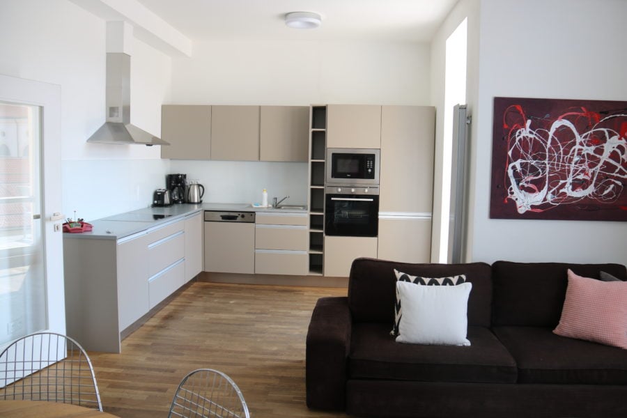 image of kitchen including long L shaped counter and full fridge in Prague family apartment