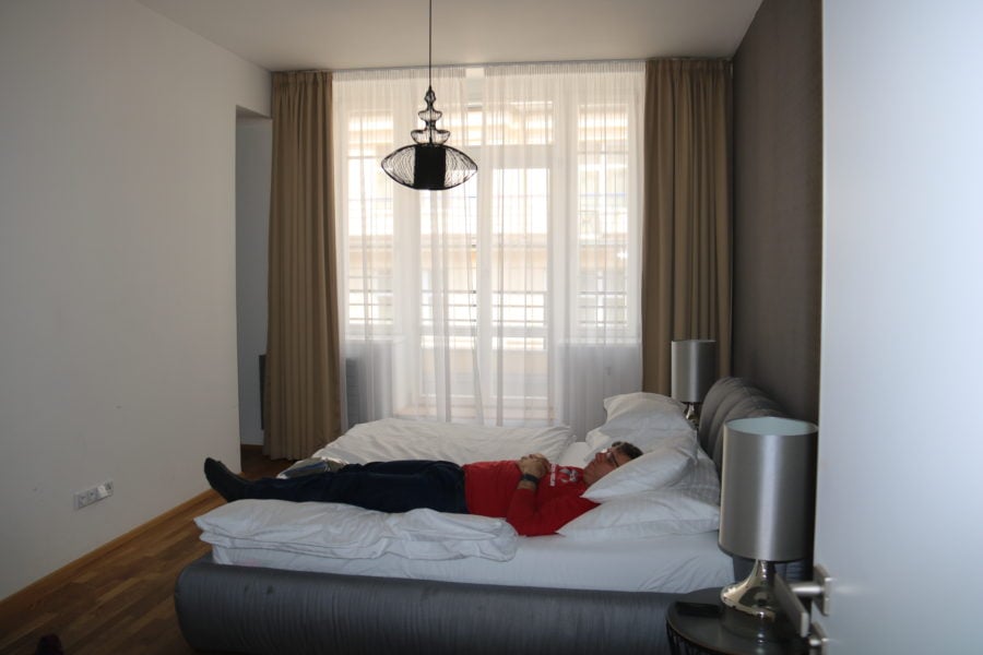image of John lying on double bed in master bedroom prague family apartment