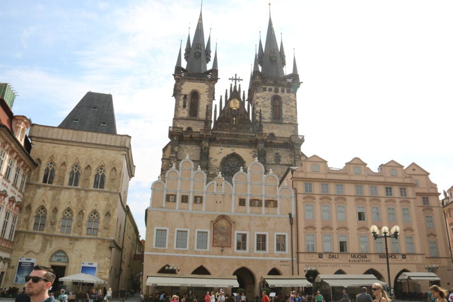 image of two spires of the Tyn church poking out from behind a set of row houses in the square
