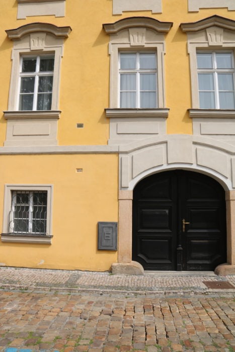 image of yellow building with double brown doors and square plaque to the right and above the door marking flood waters in prague