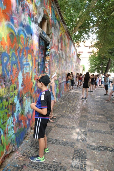 image of Caiden in front of wall reading the street art and looking for a place to put his own, Its a fun thing for kids to do in Prague