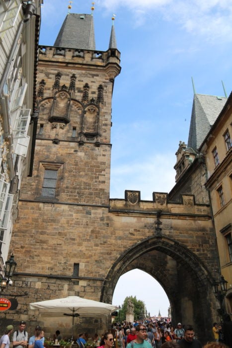 image of tower next to arch that leads to Charles Bridge Prague which is fun thing to do in Prague