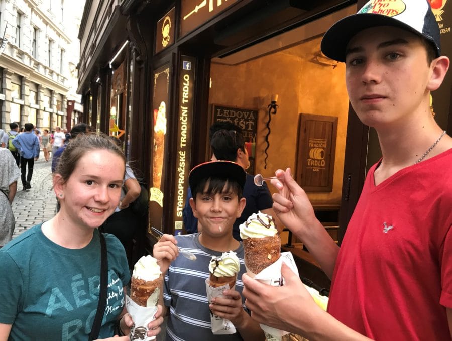 image of three children eating trdelnik which is open ended cone with ice cream and totally fun thing to do in Prague