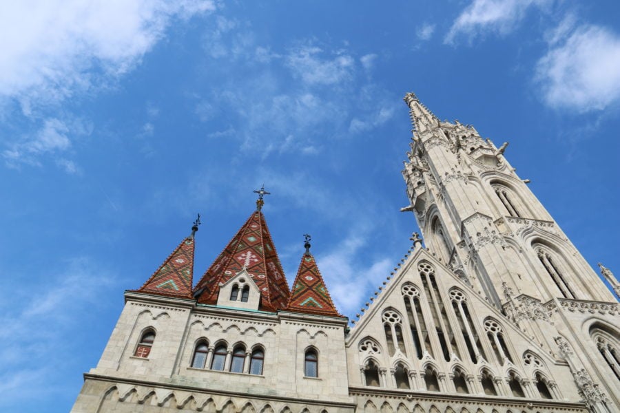 image of exterior of Matthias church in Budapest showing white decorative tower and red and green tiled lower roof.