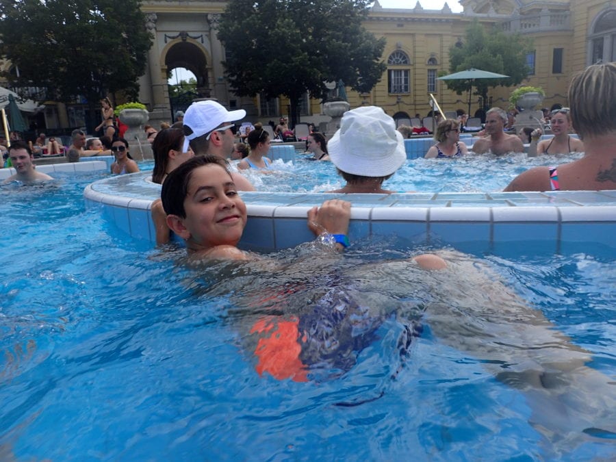 image of CJ holding on the the edge of a swirling whirlpool at Szechenyi Baths on Day 2 of our Budapest Itinerary