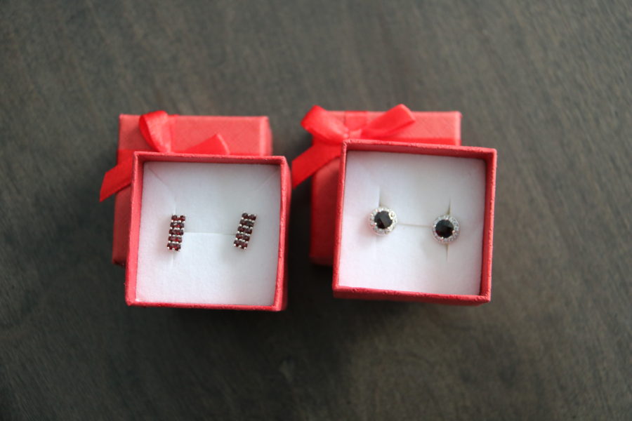 image of two pairs of garnet earrings. Both in small red boxes with bows. One with eight small garnets in a rectangular shape and one set with a larger 4mm garnet with zirconias around. shopping for garnets is fun thing to do in Prague