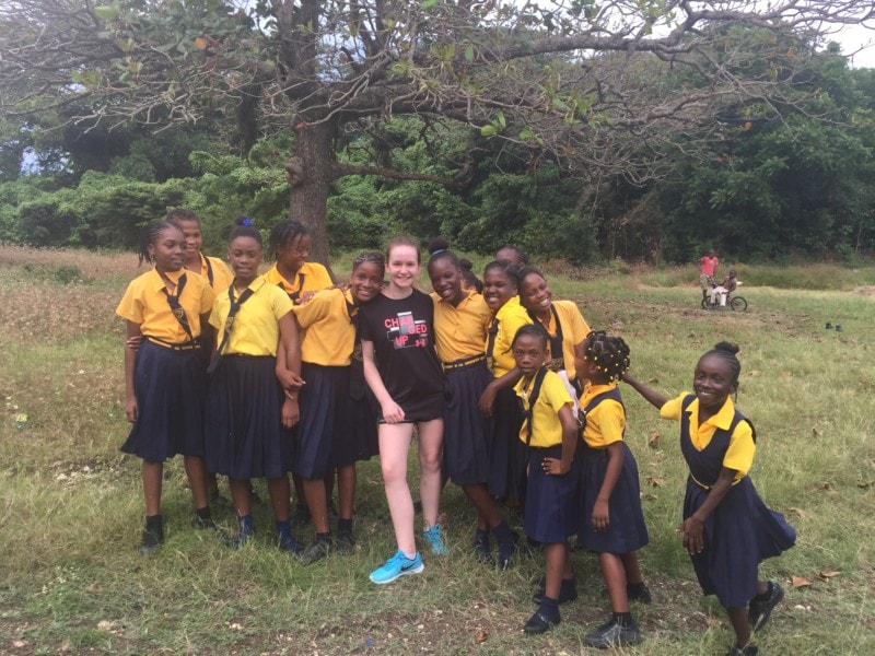 image of Sydney with the girls of Jamaica school visit in the back field