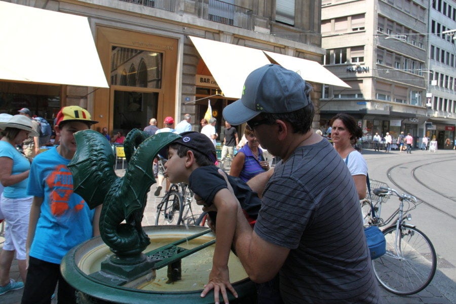 John lifting boy up to fountain like basilisk to get drink in Basel