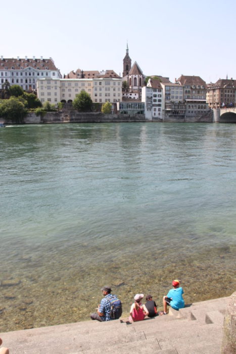kids sitting on stone stairs on the edge of the Rhine is one of best things to do in Basel