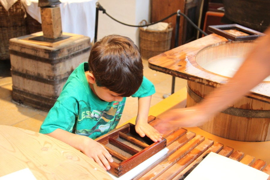 boy pressing on fresh made paper to remove water at Basel Paper Mill Museum