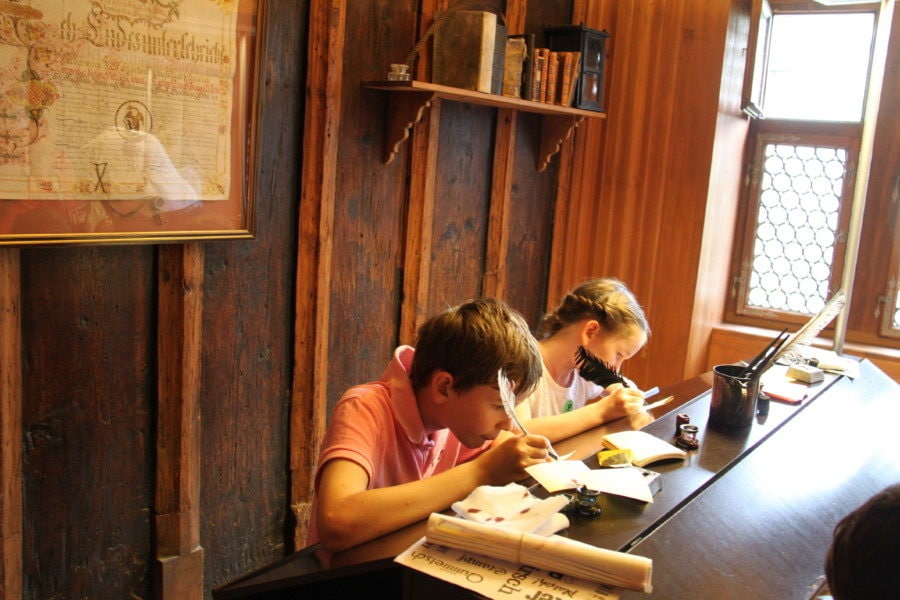Two kids writing with quill pen at Basel Paper Mill Museum