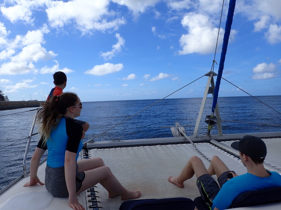girl and two boys sitting on front of barbados catamaran