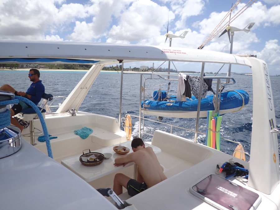 Teen sitting at picnic like table on Barbados catamaran with head in arms