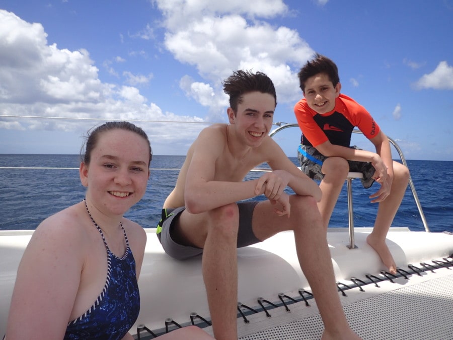 my 3 kids on front of catamaran with hair blowing great Barbados attraction
