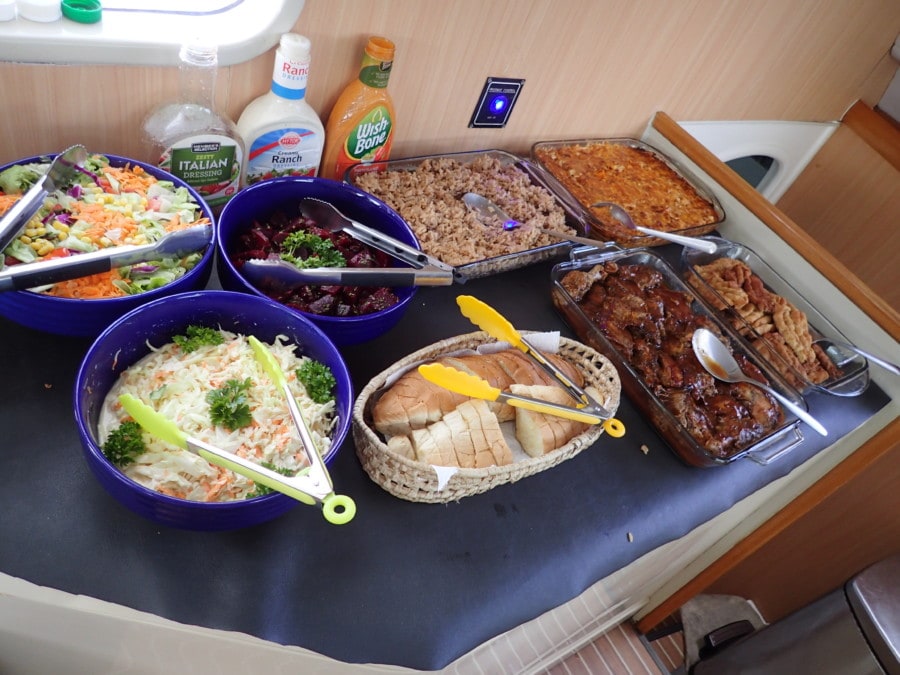 table on Barbados catamaran excursion with eight plates of food including salads and meats