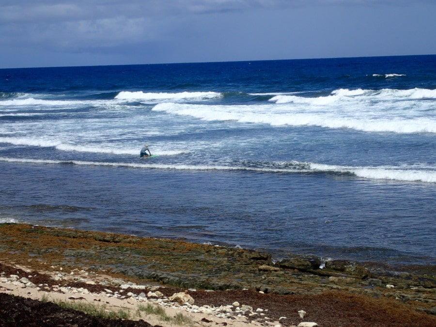 Man on surfboard entering rough ocean