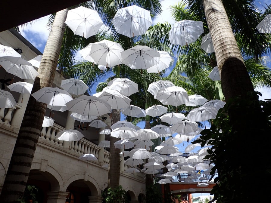 white umbrellas hanging with sky above in center court of Barbados attraction complex