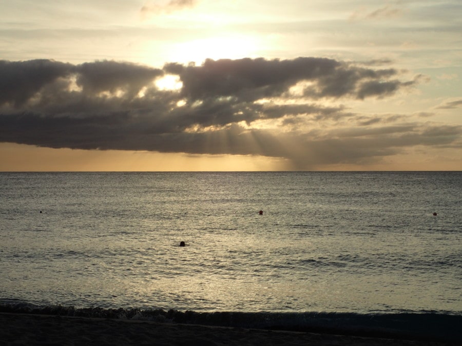 beach, water and yellow sky with rays shining through clouds at sunset in picture of Barbados