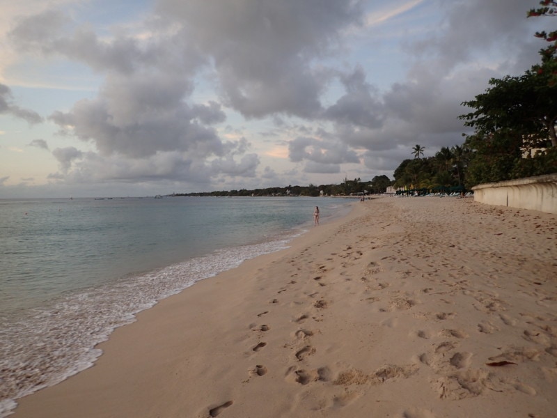 long sandy beach with footprints beside blue sea Barabados Attraction