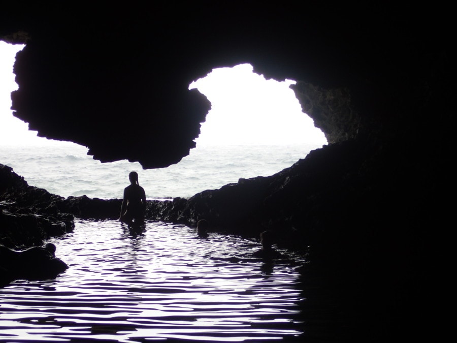 shadowed cave pool with sillouette of person in cave opening