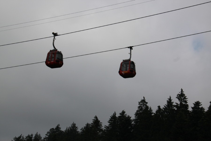 two red gondolas passing each other in air on a metal cord to top of Pilatus
