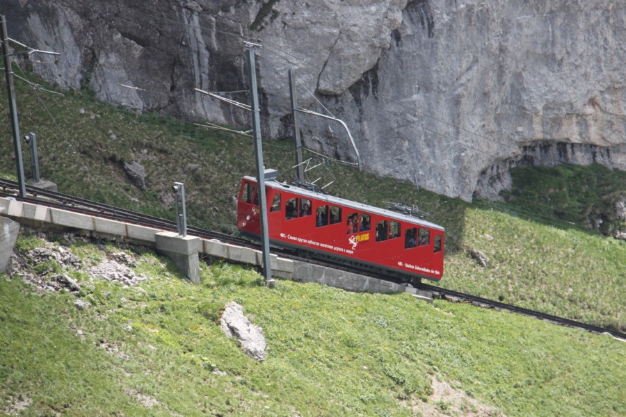 red cogwheel train car with five windows climbing steep Mount Pilatus