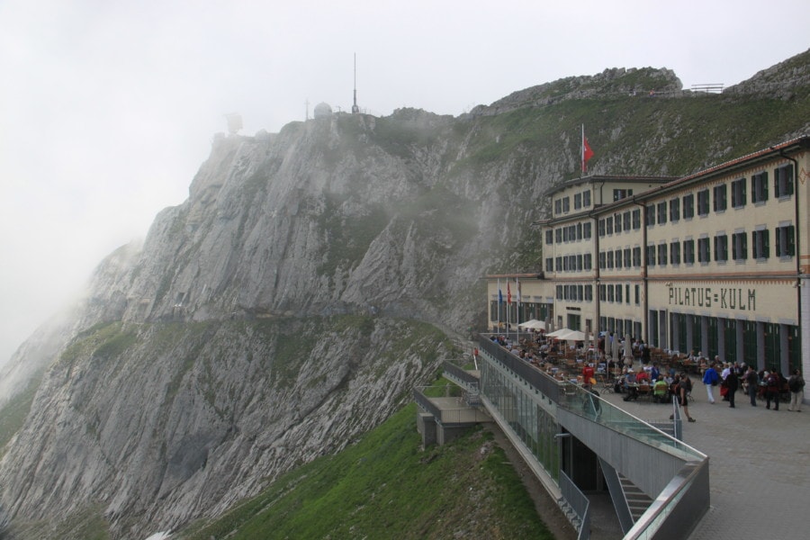 beige rectangular hotel next to large stone cliff with trails on it