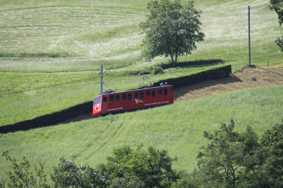 red cogwheel train going up green lush mountain that is Mount Pilatus