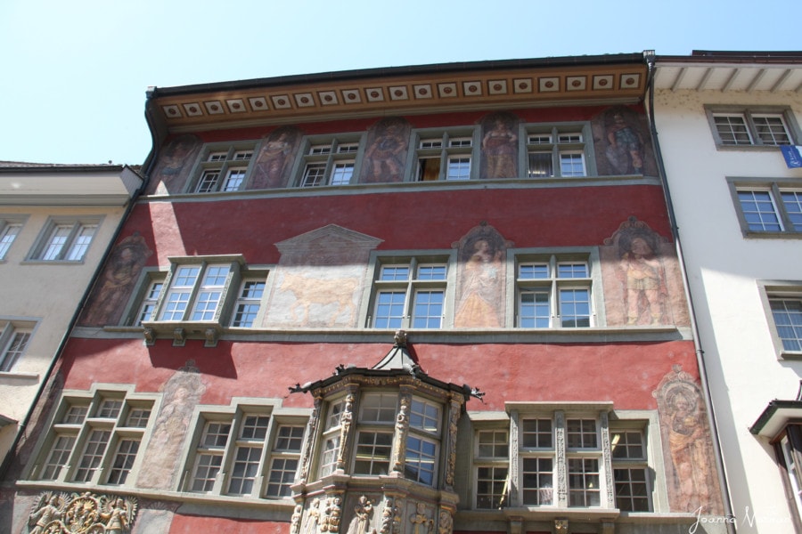 large three story orange house in Schaffhausen with windows and frescoes on each level including one of a golden ox