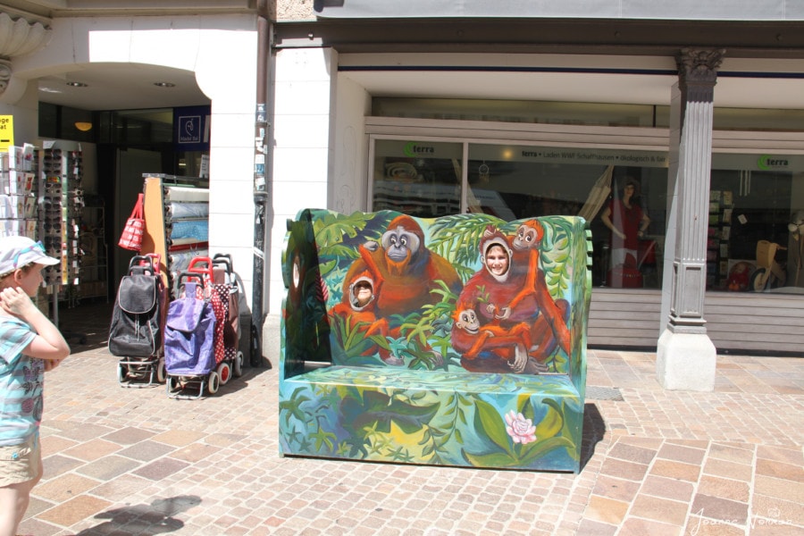 city bench painted like a jungle with two openings where kids can put their face in to look like monkeys