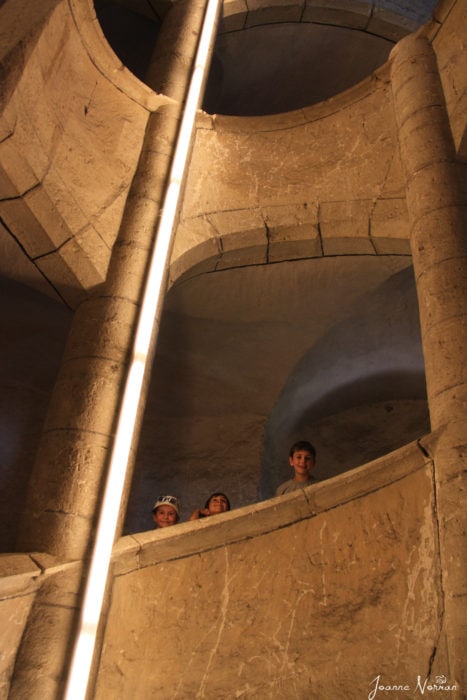 three kids looking over stone spiral stairs