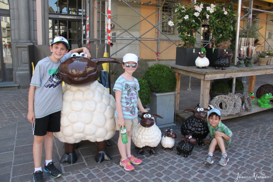 kids standing near three cute sheep statues