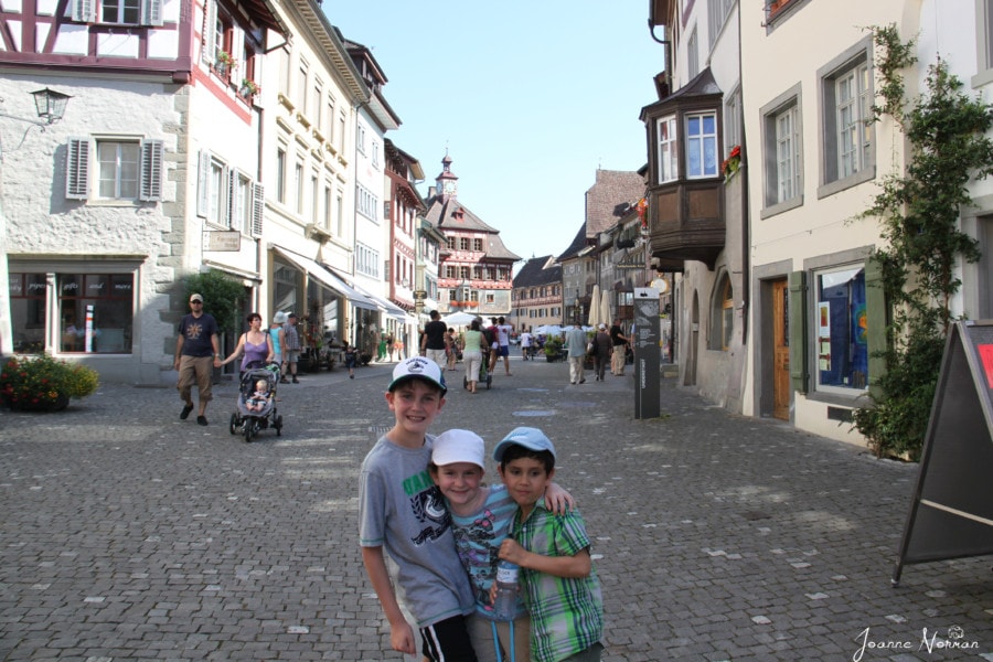 three kids on cobblestone street hugging in fun