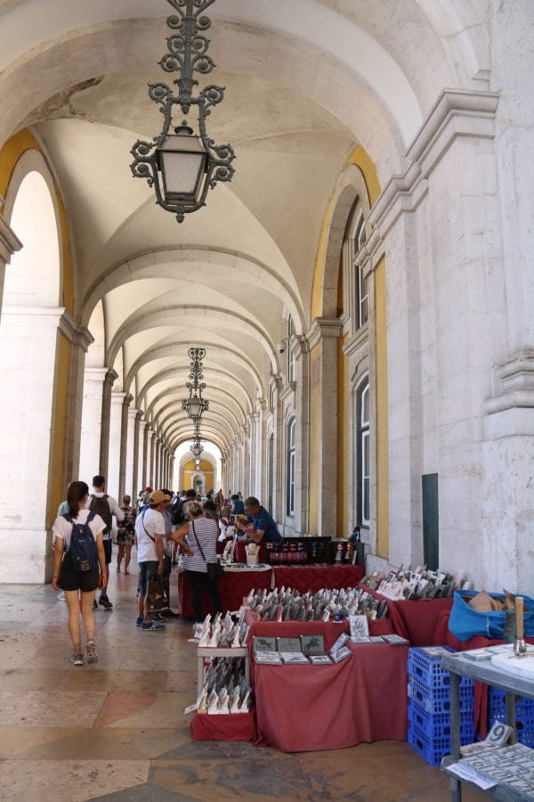 decorative hallway running under the arches of the yellow buildings alongside the Arch with tables set up with handicrafts
