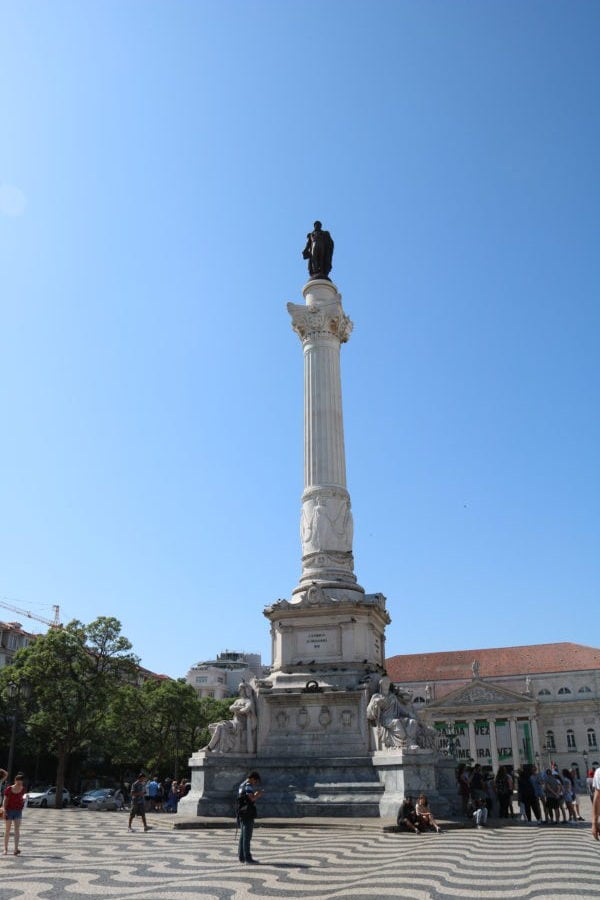 tall stone base with man standing on top in Rossio Square