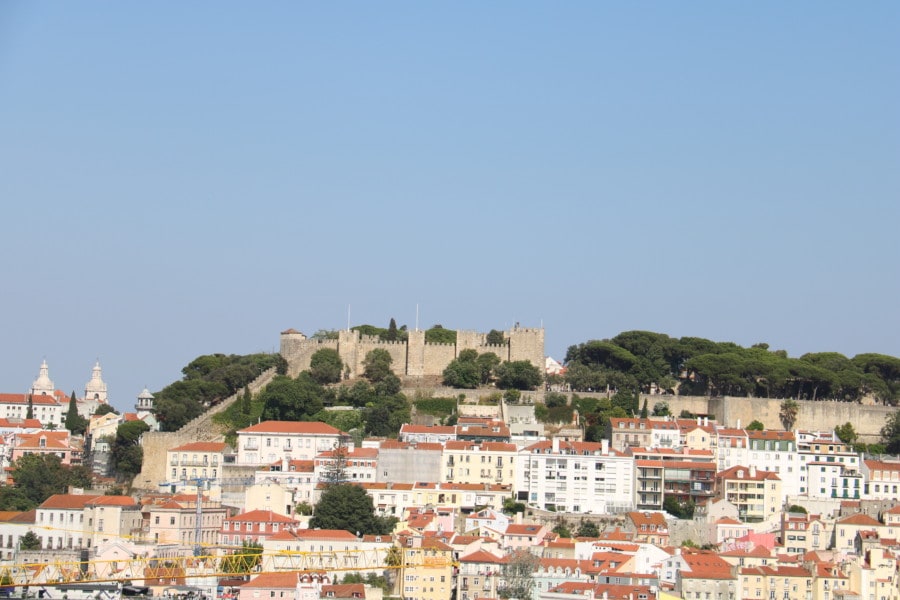 view overlooking orange roofs of Lisbon with castle on top of hill great Lisbon with kids