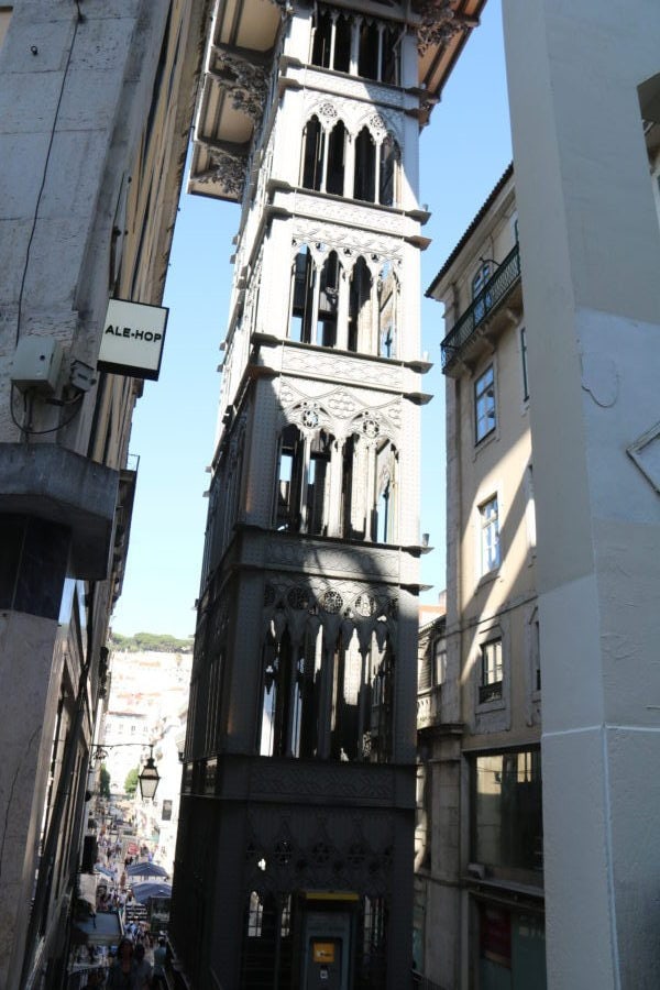 in middle of street a tall several story elevator with lacy like steel Elevador Santa Justa