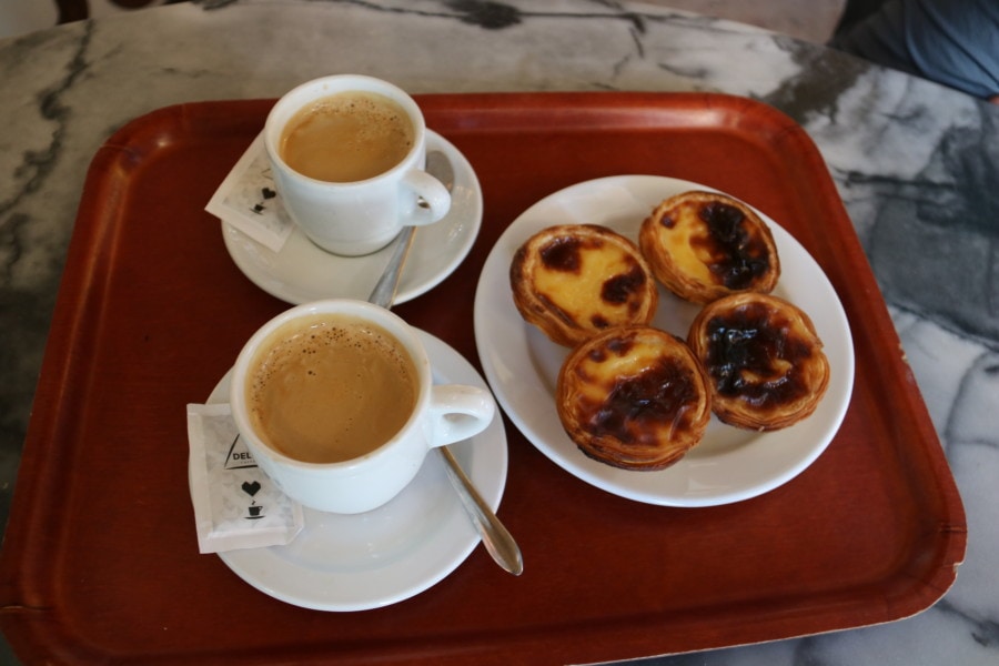 custard tarts and two coffee on a red tray