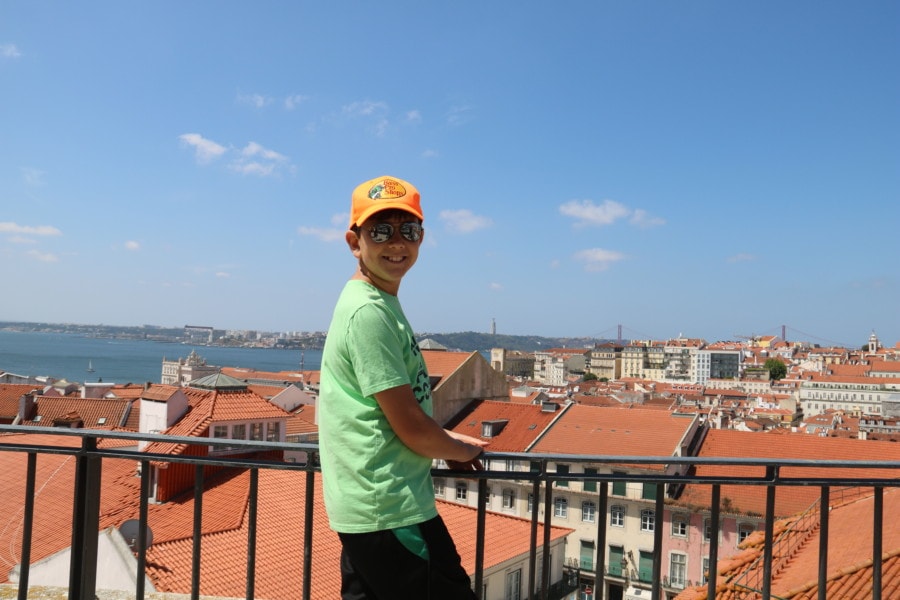Caiden next to railing with view of river and orange rooftops